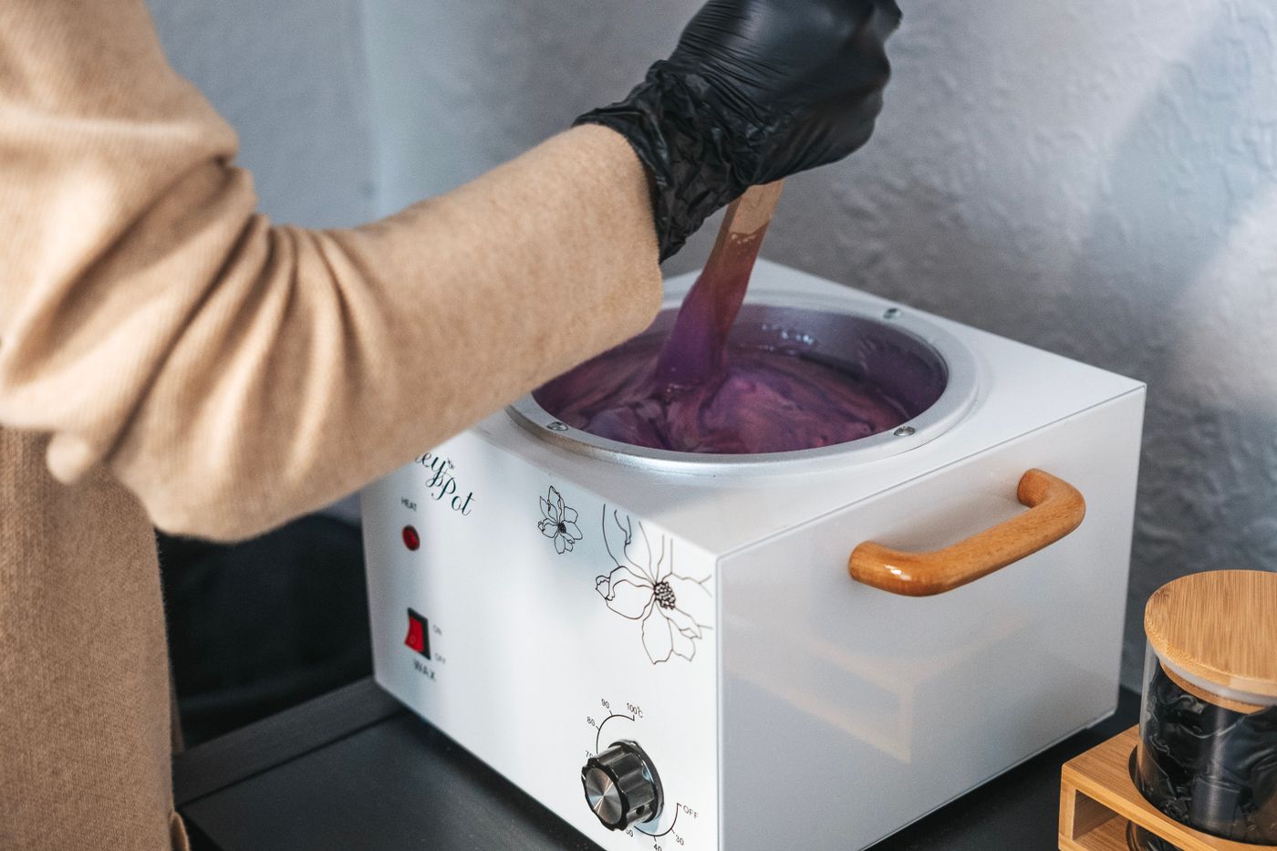 Warm wax being stirred in a wax heater before a waxing session in Dubai